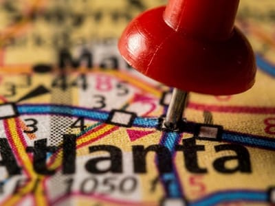 Red push pin stuck into Atlanta on a folded road map